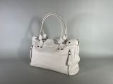 the white purse is sitting on the table on a gray surface