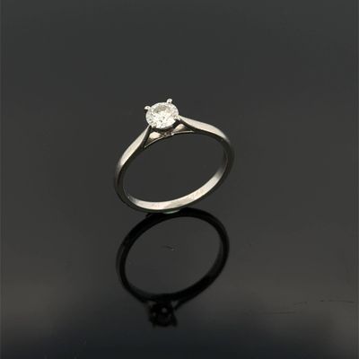 a single stone diamond ring on a black surface