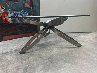 une table en verre avec des pieds en métal et un plateau en verre