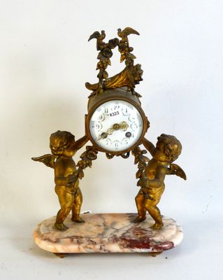 a small clock with angels on it on a marble base