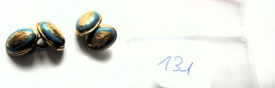 une paire de boucles d'oreilles bleues et dorées posées sur un morceau de papier