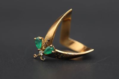 gros plan d'une bague en or avec une pierre verte