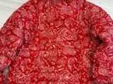 une veste rouge à motifs cachemire posée sur une table blanche