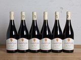 six bouteilles de vin rouge alignées sur une table en bois