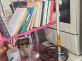 une étagère rose sur laquelle se trouvent des livres et un balai