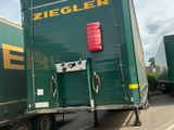un gros camion vert avec un tonneau rouge à l'arrière