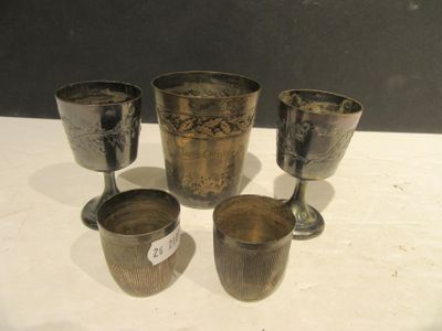 quatre gobelets et tasses en argent posés sur une table, accompagnés d'une étiquette de prix