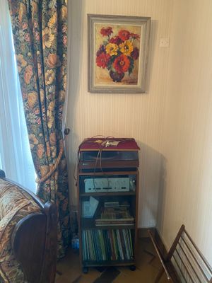 une pièce avec un canapé, un fauteuil, une bibliothèque et un tableau accroché au mur