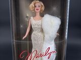 the barbie doll is in a clear box with a fur stoler