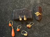 four pairs of earrings and a ring on a black surface