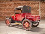 a old red car parked in front of a brick wall