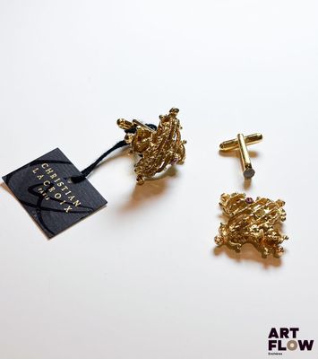 deux paires de boucles d'oreilles en or représentant un livre et une croix sur un fond blanc
