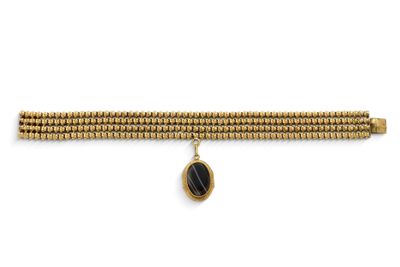 un bracelet en or orné d'un pendentif en pierre noire