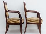 two wooden chairs with striped upholstered seats against a white wall