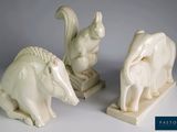 Deux statues d'animaux sont posées l'une à côté de l'autre sur une surface blanche.