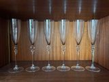six empty wine glasses lined up on a shelf in a room