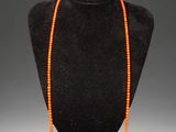 an orange beaded necklace on a black mannequin