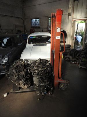 a white car in a garage with other cars in the background