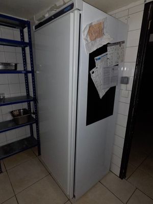 un réfrigérateur dans un coin d'une pièce, avec des étagères fixées au mur