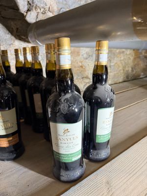 several bottles of wine are lined up on a wooden shelf