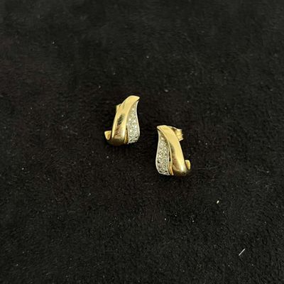 a pair of gold and diamond earrings on a black surface