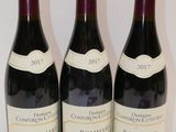trois bouteilles de vin sont alignées sur une surface blanche