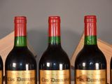 six bottles of red wine are lined up on a table