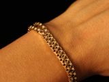 quelqu'un tient un bracelet en chaîne d'or à son bras