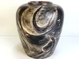 un vase noir et blanc posé sur une surface blanche