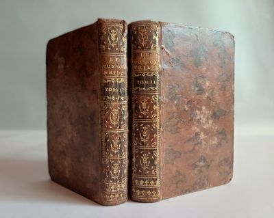 un vieux livre posé sur une table à côté d'un mur blanc