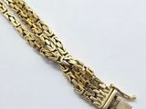 a close up of a gold chain bracelet on a white surface