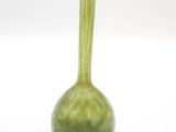 un vase vert posé sur une surface blanche