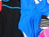 three swimsuits on a bed next to a pair of shoes