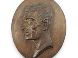 un médaillon ancien en bronze représentant le visage d'un homme sur fond blanc