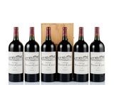 four bottles of red wine sit in front of a wooden box