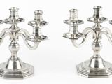 une paire de chandeliers plaqués argent sur des socles, sur fond blanc