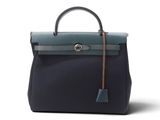 un sac à main noir et bleu dont la poignée est ornée d'un pompon