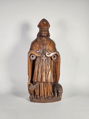 une vieille statue en bois représentant un homme tenant un chien dans ses bras