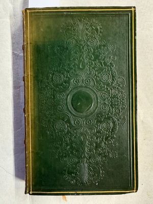 un vieux livre vert posé sur une table blanche