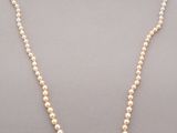 a white pearl necklace with a green stone clasp