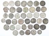 an assortment of old silver coins on a white surface
