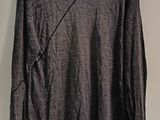 grey long - sleeved shirt hanging on a hanger on a wall