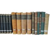 several old books are lined up in a row on a white surface