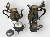 two silver plated teapots and a silver plated spoon on a white surface
