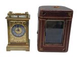 une petite horloge posée à côté d'une petite boîte sur une surface blanche