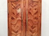 une armoire ancienne en bois, dont les portes sont ornées de ferrures en laiton