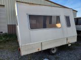 a small white trailer parked in front of a building