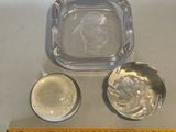 a glass ashtray and a silver ashtray on a table next to a ruler