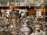 une vitrine remplie de théières en argent et d'autres objets