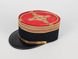 un chapeau rouge et noir orné d'un emblème doré